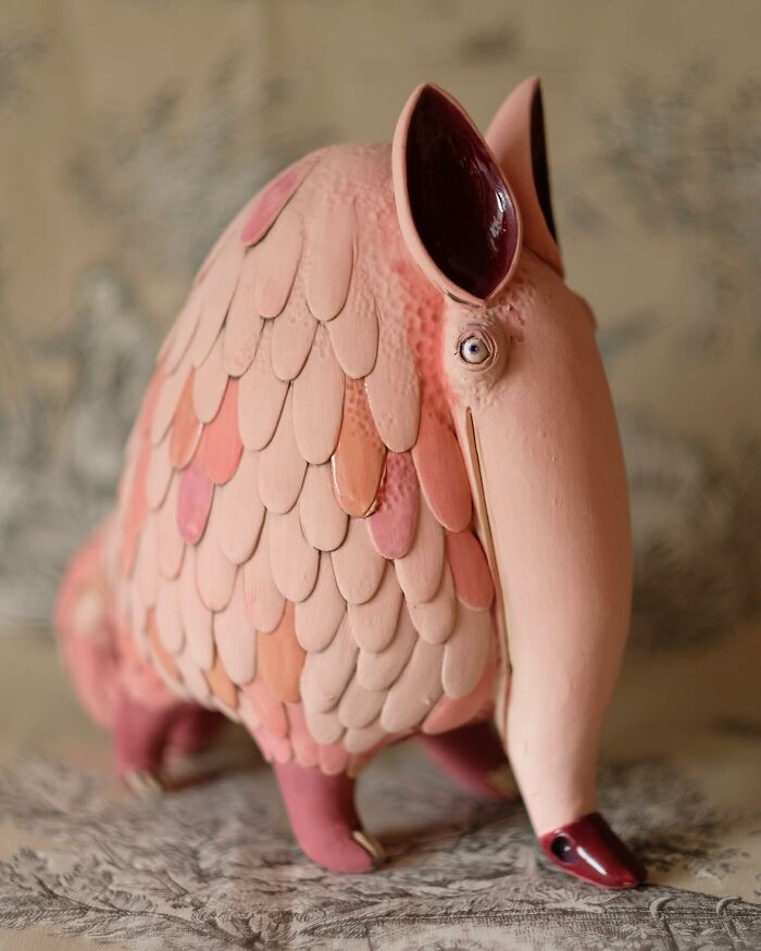 Playful ceramic sculpture by Nastia Calaca, featuring a whimsical, pink armadillo-like creature with textured details.
