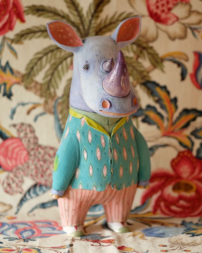 Playful ceramic sculpture of a rhino in colorful attire, set against a vibrant floral background.