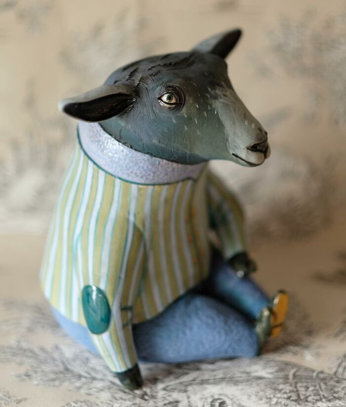 Playful ceramic sculpture of an animal with a striped shirt and blue pants, created by Nastia Calaca.