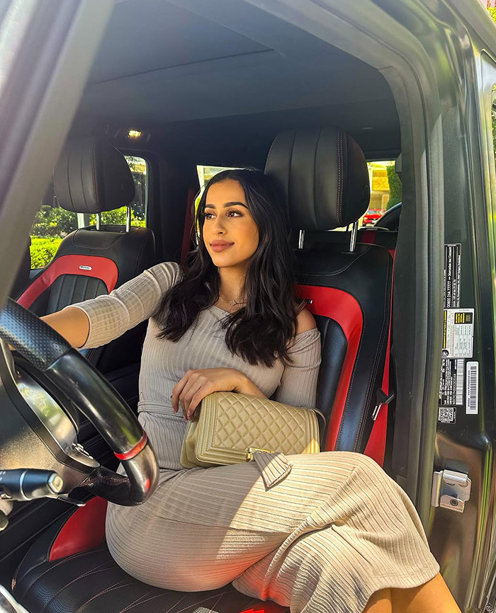 Dubai housewife Linda Andrade in a luxury car holding a designer bag, reflecting a materialistic lifestyle.
