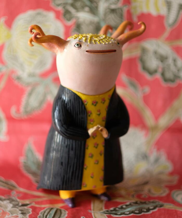 Playful ceramic sculpture with whimsical design, featuring unique creature, colorful clothing, and intricate background detail.