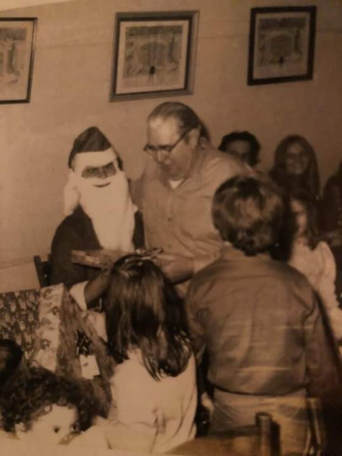 Vintage scene featuring a creepy Santa with children and an adult in a dimly lit room.