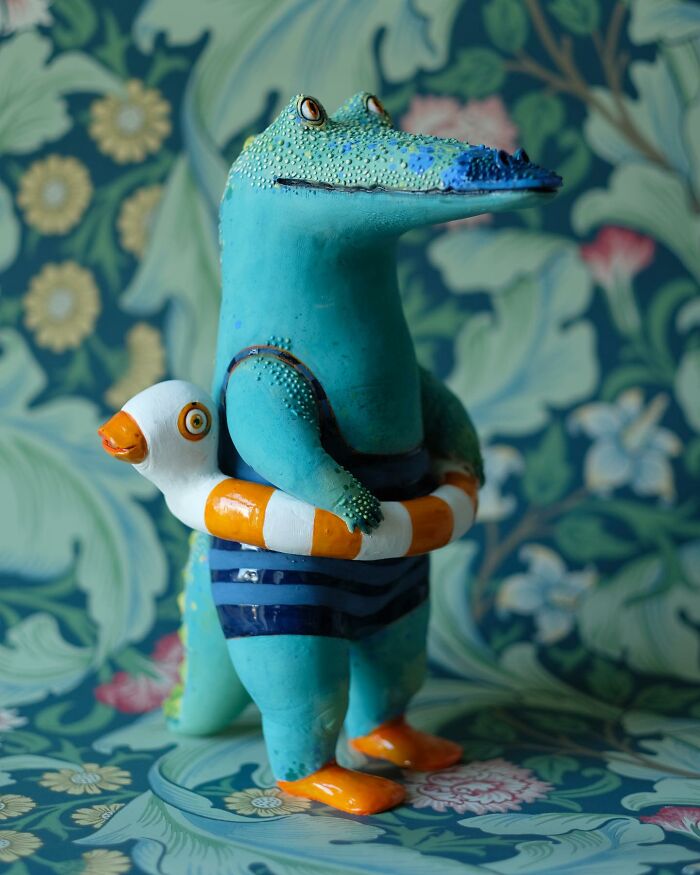 Ceramic sculpture of an alligator in a swimsuit holding a life ring, by Nastia Calaca.