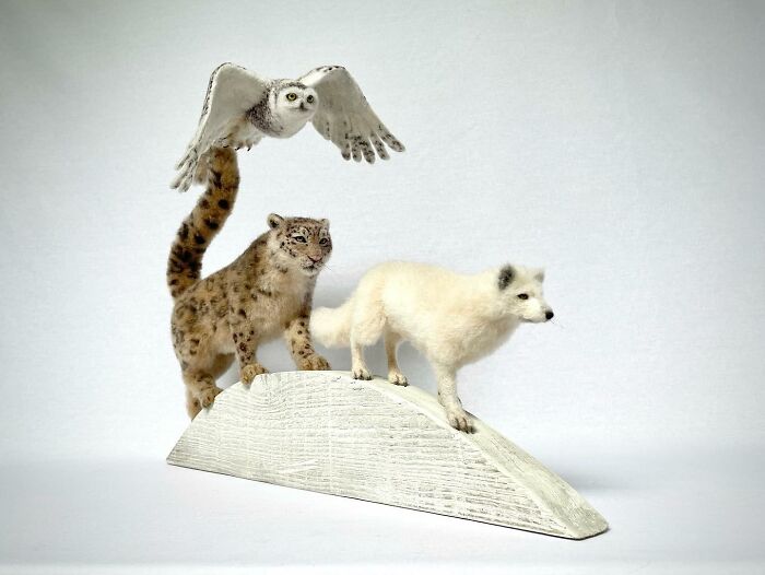 Needle-felted animals including an owl in flight, a snow leopard, and an arctic fox on a white base.