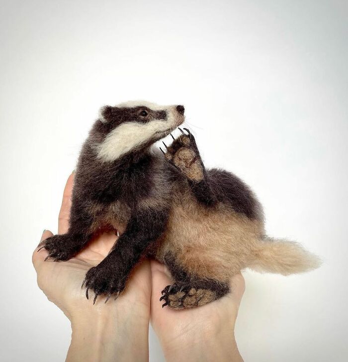 Needle-felted badger in hands, showcasing intricate artistic detail.