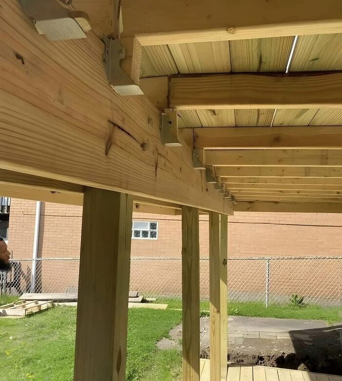 Unstable wooden deck with misaligned beams showcasing funny cheap construction fails.