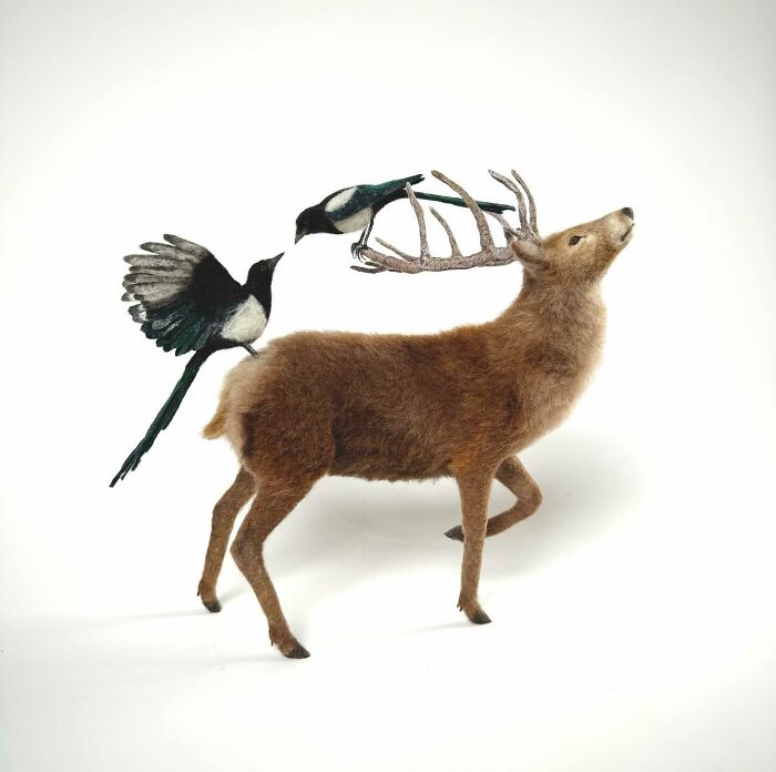 Needle-felted deer and magpies in a whimsical pose showcasing artistic animal creations.