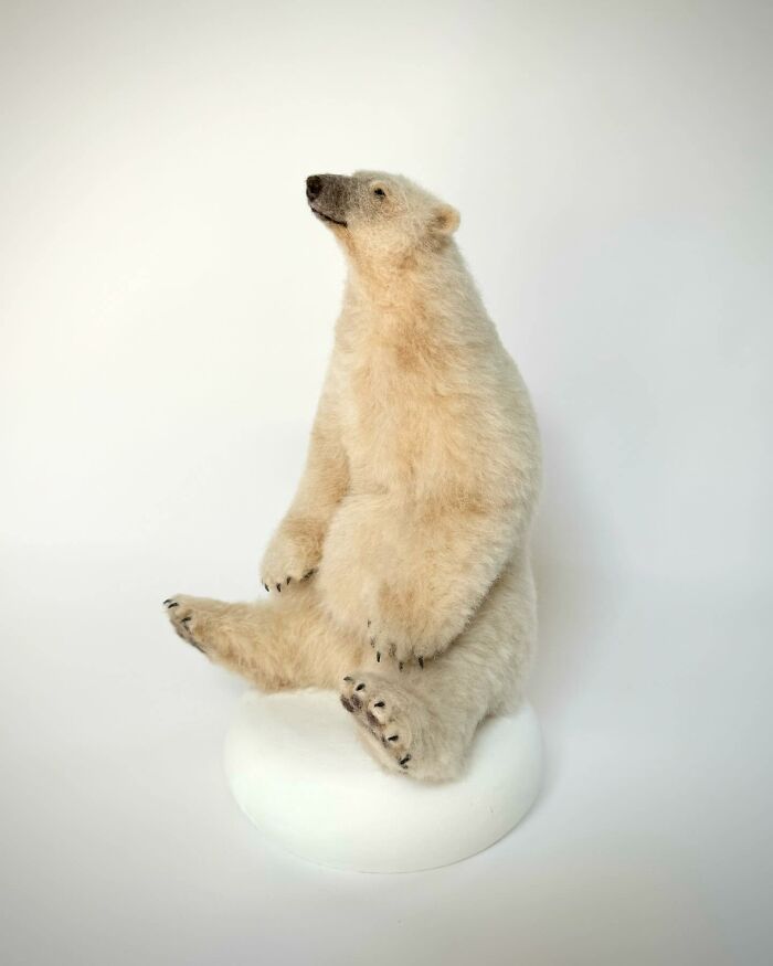 Needle-felted polar bear sculpture by artist, showcasing intricate wool craftsmanship on a plain background.