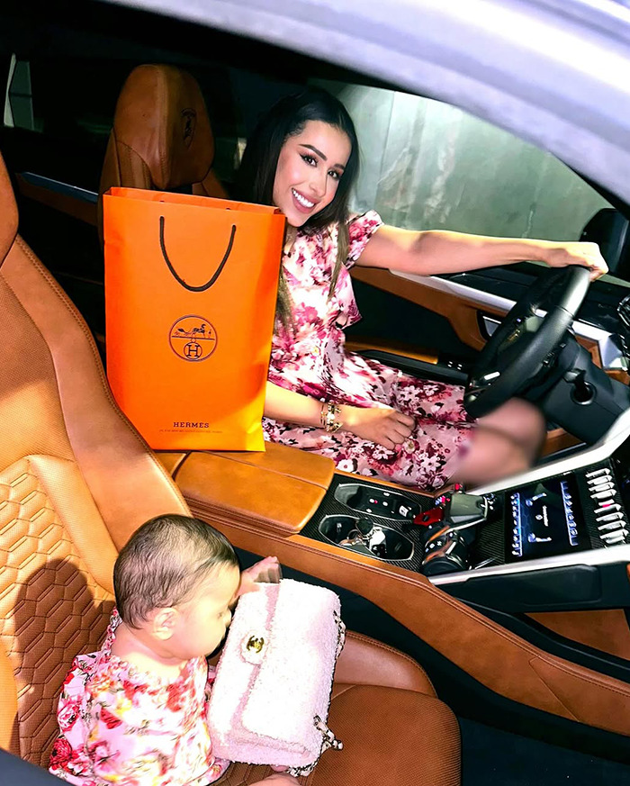 Dubai housewife in luxury car with Hermes bag and child, surrounded by Christmas gifts.