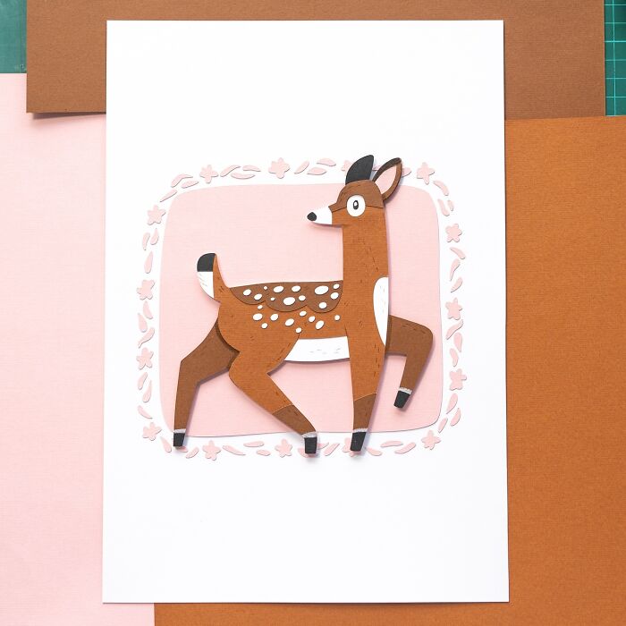 Layered paper illustration of a cute deer on a pink background, showcasing intricate artwork.