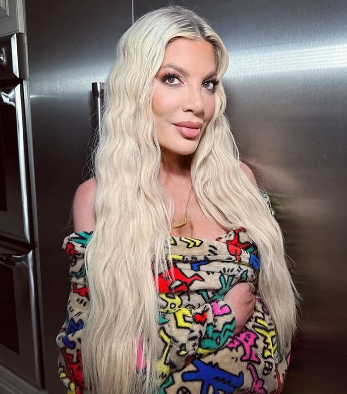 Tori Spelling in colorful outfit standing in a kitchen