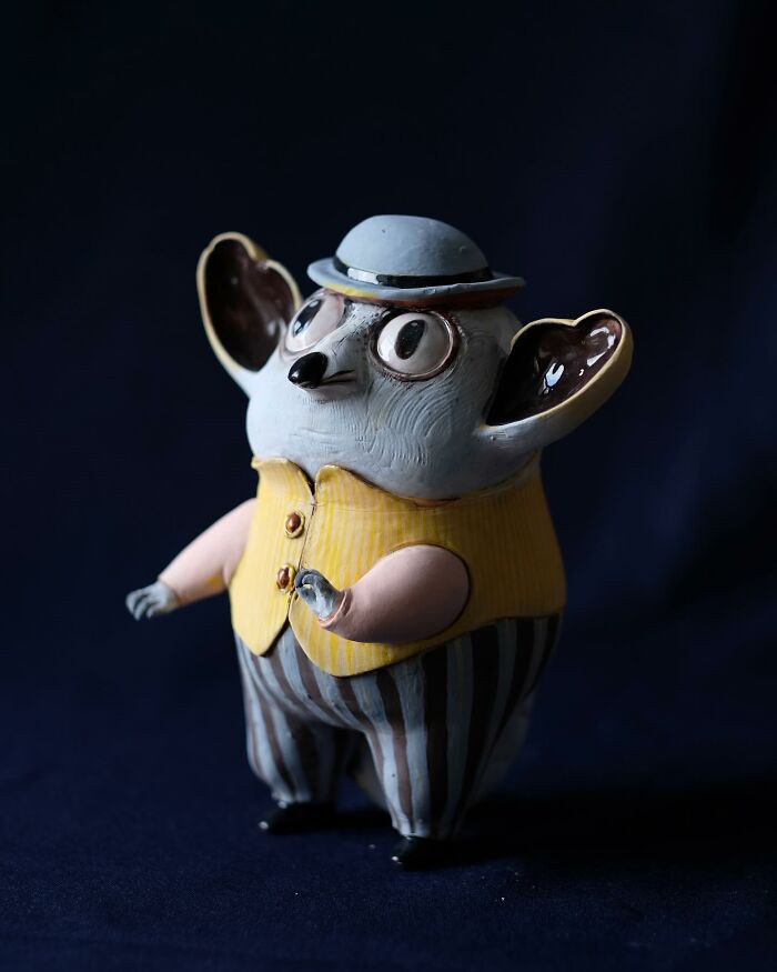 A playful ceramic sculpture of a cartoonish animal wearing a striped outfit and hat by Nastia Calaca.