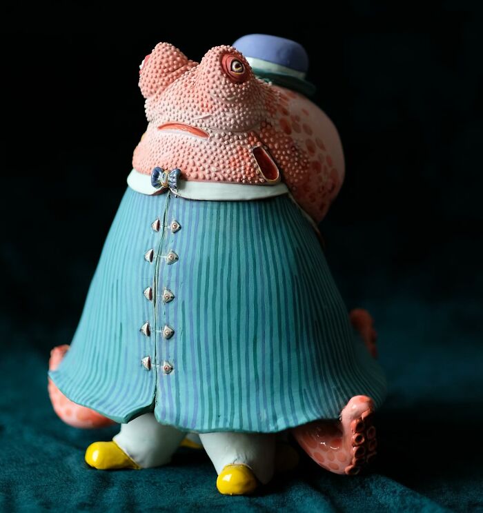 Playful ceramic sculpture of a creature in a blue-striped outfit with a hat, showcasing artistic creativity.