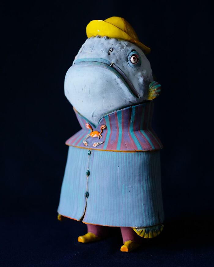 Playful ceramic sculpture of a fish wearing a coat and hat, designed by Nastia Calaca.