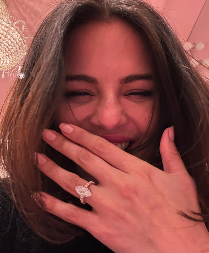 Selena Gomez smiling with hand over mouth, showing a large diamond engagement ring.