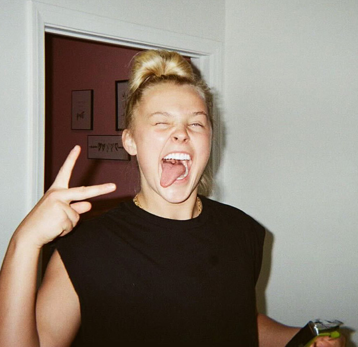 JoJo Siwa in black top, posing playfully.