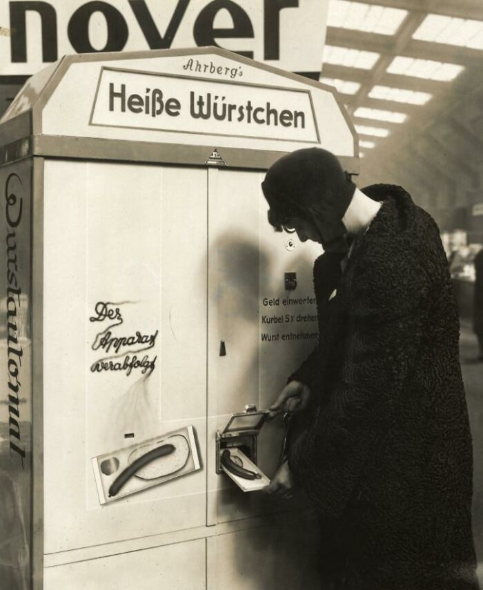Person using vintage sausage vending machine, a strange invention.