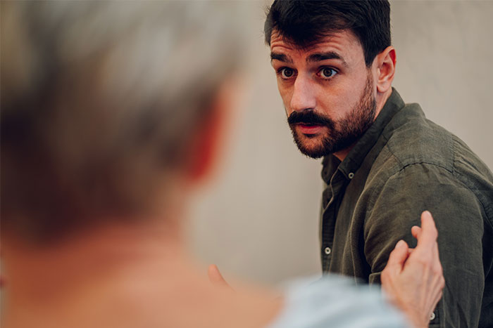 Man in a dark shirt talking to an older woman, discussing wedding dress choice for comfort.
