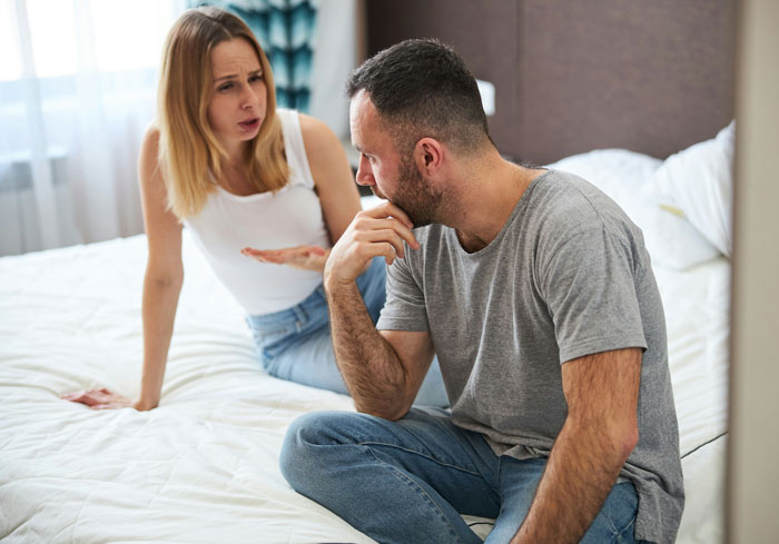 Couple arguing on bed, husband looking thoughtful, represents tension over baking and liking Taylor Swift. Couple arguing on bed, husband looking thoughtful, represents tension over baking and liking Taylor Swift.