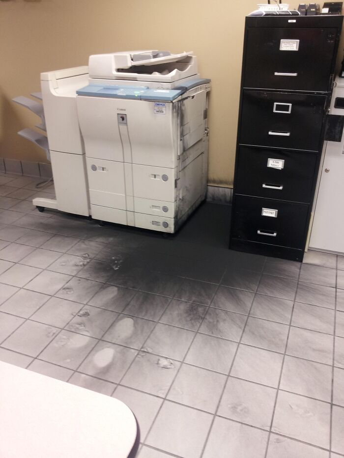 Office copier toner spill creating a really messed up moment with black powder covering the floor and footprints visible.