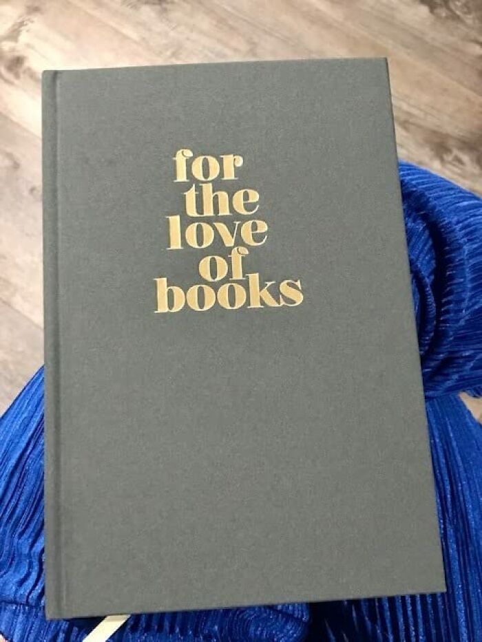Gray hardcover book with gold lettering saying for the love of books on a blue fabric background, a coolness item to covet.