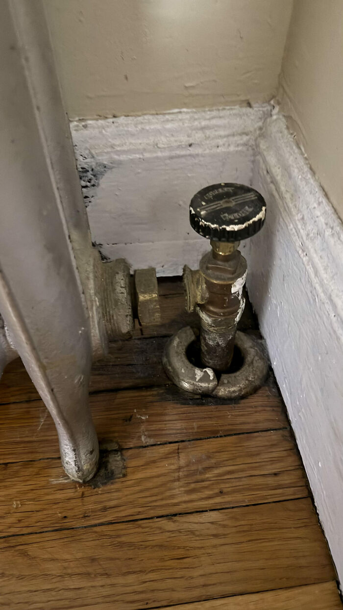 Funny construction fail with a misaligned heating valve protruding through a hardwood floor.