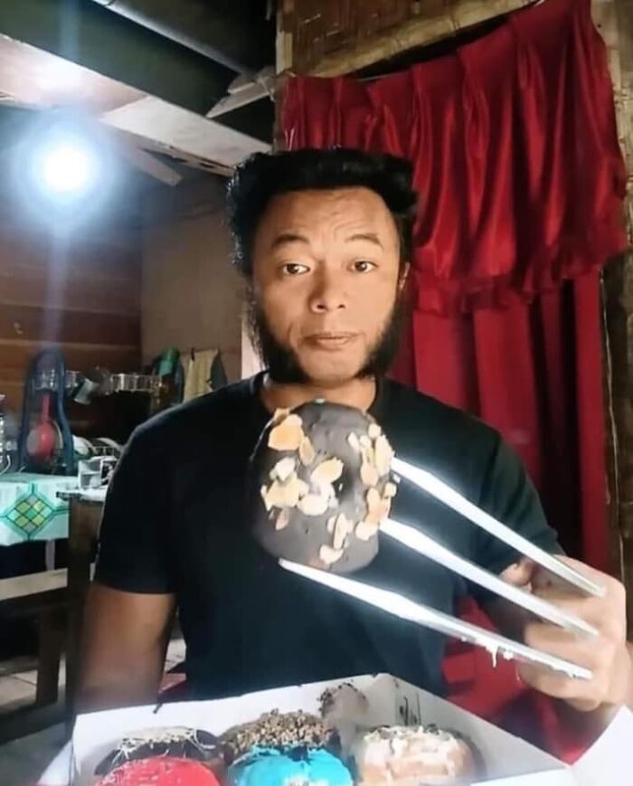 Man holding a doughnut with tongs, posing in a room with a red curtain, resembling an album cover concept.