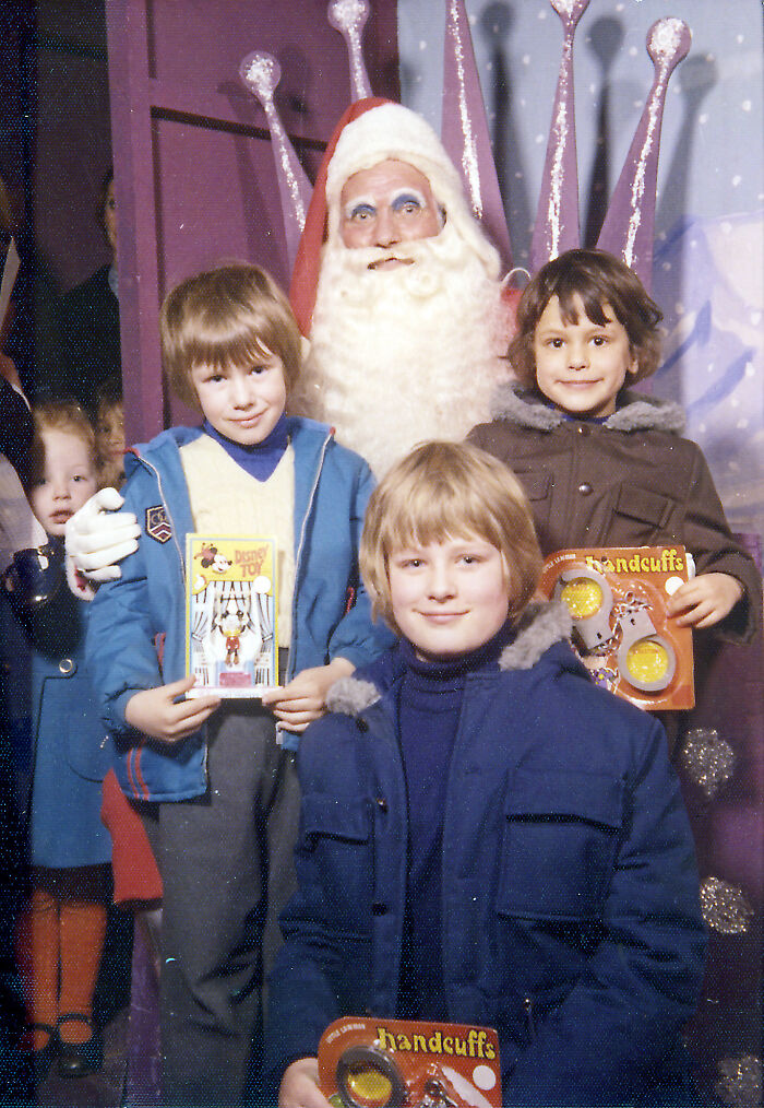 Kids posing with a Creepy-Santa, holding gifts, with a whimsical backdrop.