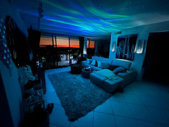 Cozy living room with ambient lighting, perfect for NYE hosting tips. Panoramic sunset view through large windows.