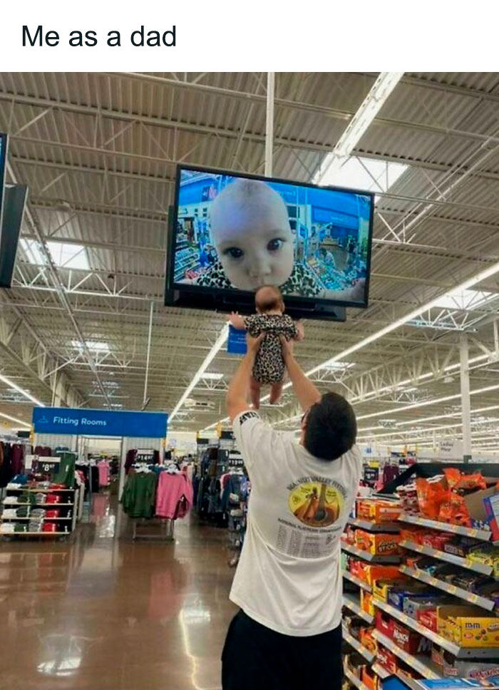 Dad holding baby in store aisle, baby on screen, humorous meme moment.