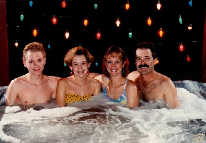 Family posing in a hot tub with colorful lights, showcasing an awkward family photo moment.