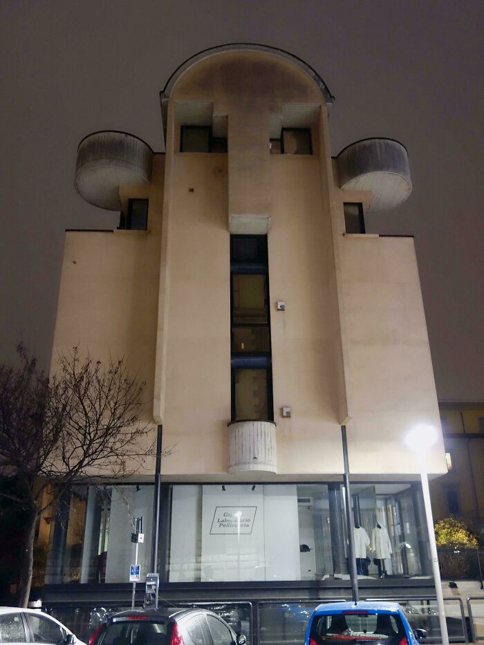 Unique bizarre building at night with unconventional architectural design and rounded extensions on upper floors