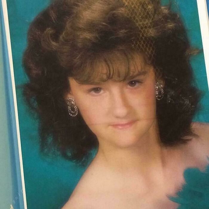 Person in glamorous attire from their blunder years, with curly hair and statement earrings.