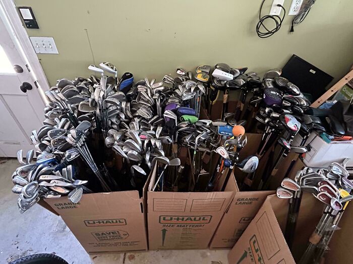 Large collection of golf clubs packed in U-Haul boxes, showcasing a unique and cool inheritance received by someone.