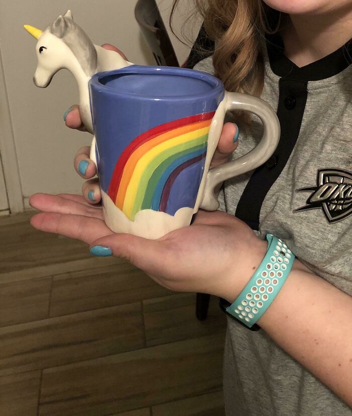 Person holding a unicorn mug with a rainbow design, showcasing a creative gift idea for amazing mothers-in-law.