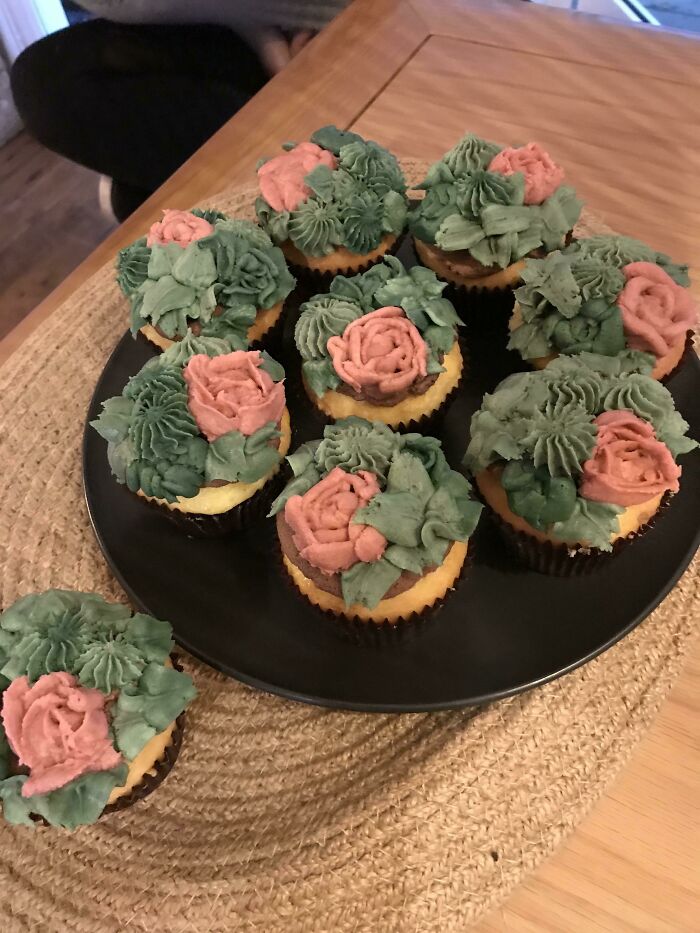 Cupcakes with rose-like frosting decoration on a black plate, showcasing amazing creativity and style.