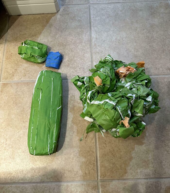 Oddly wrapped gifts in green paper on a tiled floor, showcasing hilarious in-laws' humor.