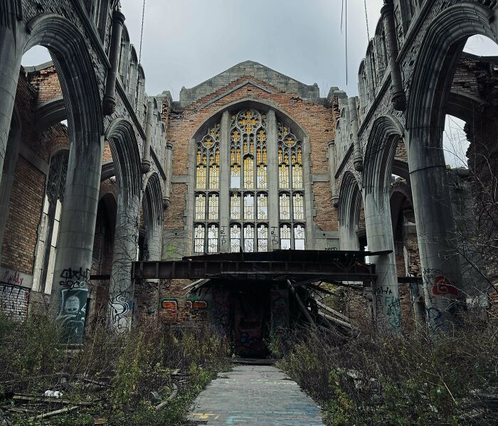 Abandoned urban hellscape featuring a decaying Gothic structure with graffiti and overgrown vegetation.