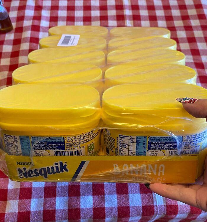Nestlé Nesquik Banana Milkshake Mix, bulk pack on checkered tablecloth, showcasing vibrant yellow lids.