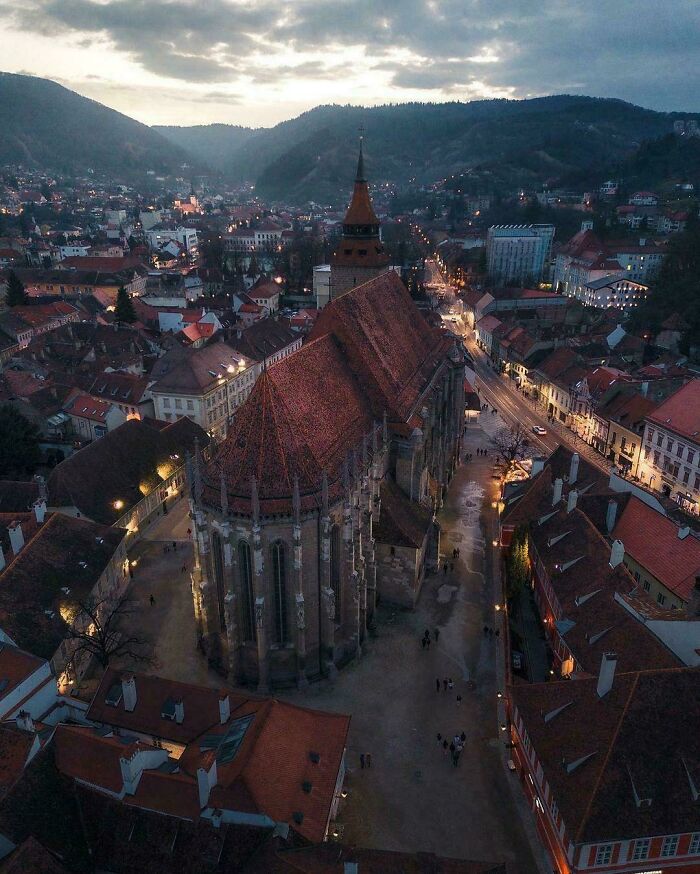 Aerial view of an impressive architectural feat, a large historic church surrounded by buildings at dusk.