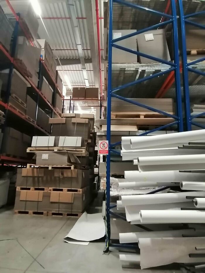 Warehouse with improperly stacked pallets and scattered materials showing employees ignoring safety protocol risks.