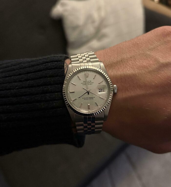 Silver Rolex watch on wrist, showcasing a cool inheritance piece in a casual indoor setting.