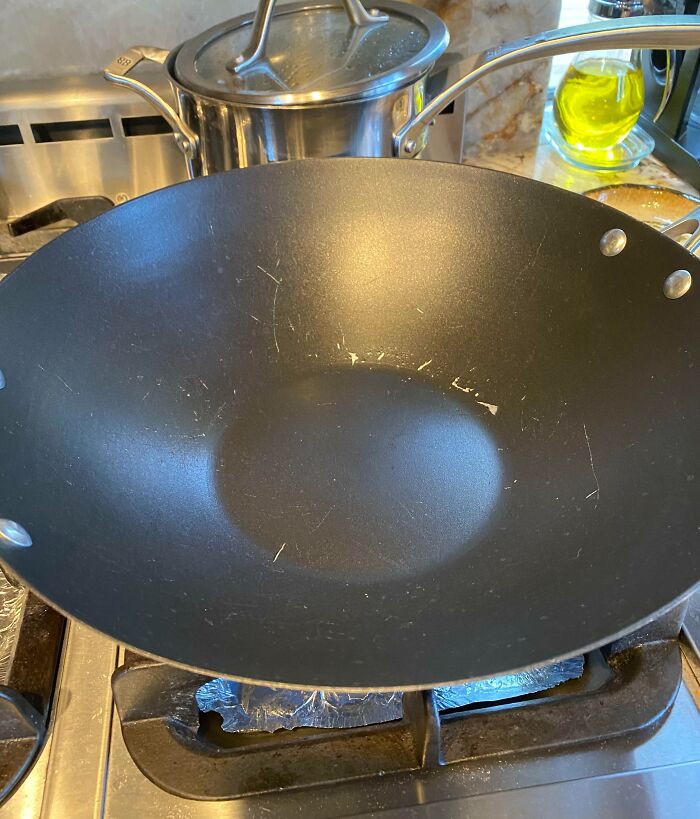 A scratched cooking wok on a stovetop possibly left by infuriating family members.