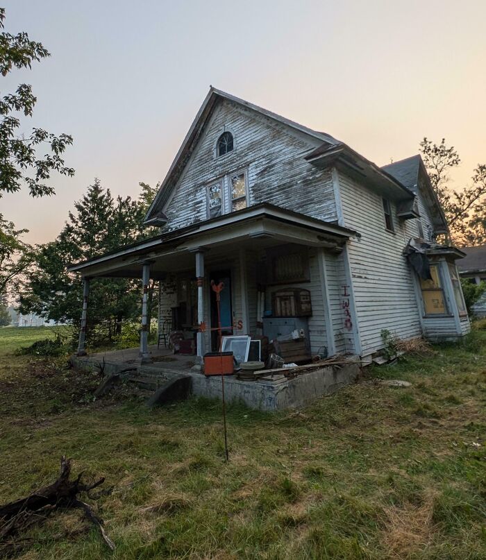 Old abandoned house with weathered wood siding and overgrown yard, part of a cool inheritance shared by people