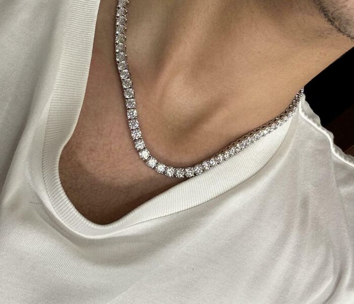 Close-up of a person wearing a diamond necklace as a cool inheritance they received, shown over a white shirt.