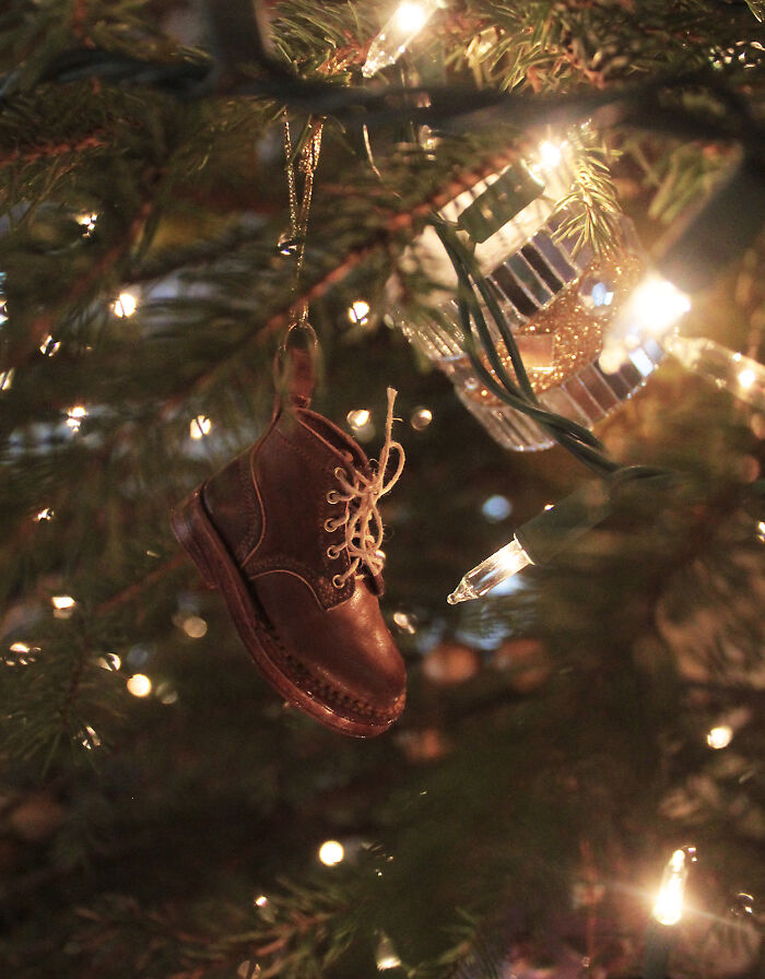 Mini leather boot as a Creative DIY Christmas decoration hanging on a tree branch amidst glowing lights.