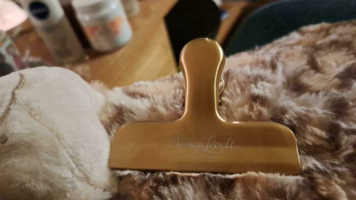 Close-up of a large metal clip attached to a plush blanket, reflecting a hilarious Christmas gift idea.