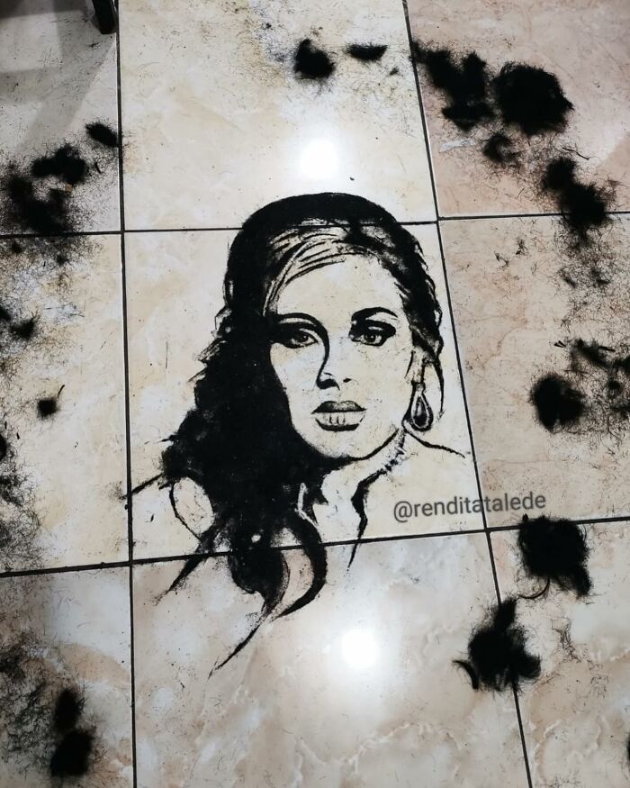 Creative portrait art on a floor using cut hair, showcasing a woman's face with detailed features.