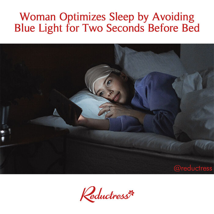 Woman in bed under covers, wearing a sleep mask, looks at phone emitting blue light, capturing a fake headline moment.