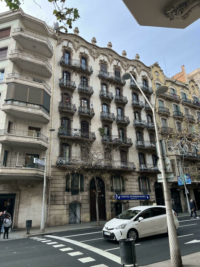 Ornate historic building facade with intricate balconies on a city street, showcasing impressive architectural feats.